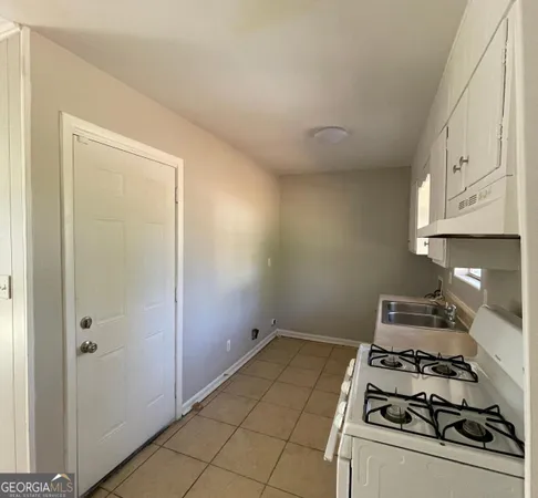 a kitchen with granite countertop a stove a sink and white cabinets
