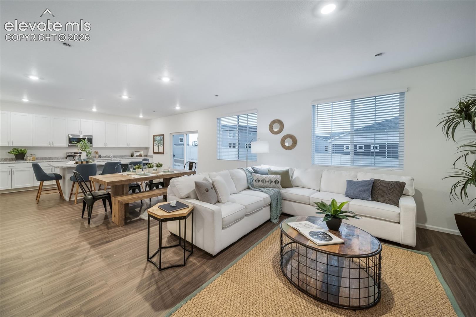 4936 Truscott Road Colorado Springs, CO 80925 - Photo 19 of 41 Open-concept living area featuring wood-finish flooring, white cabinetry, a kitchen island, recessed lighting, and large windows
*photos of a model home*