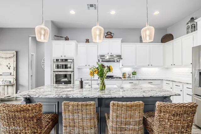 a kitchen with stainless steel appliances granite countertop a stove a sink dishwasher a dining table and chairs with wooden floor