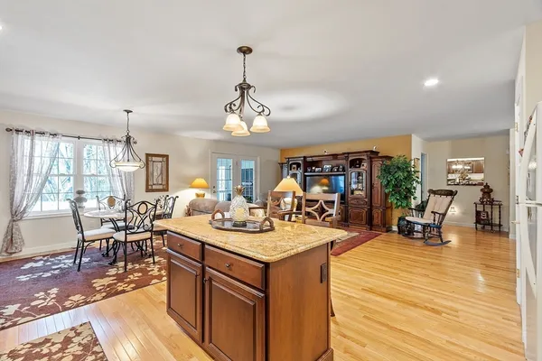 a view of a dining room and livingroom with furniture wooden floor a rug a flat screen tv a rug and a chandelier
