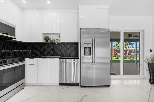 a kitchen with stainless steel appliances granite countertop a refrigerator a stove a sink and a microwave