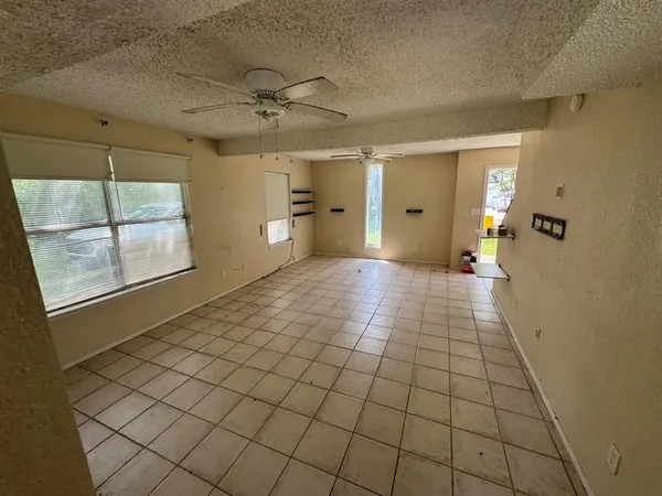 an empty room with windows and a ceiling fan