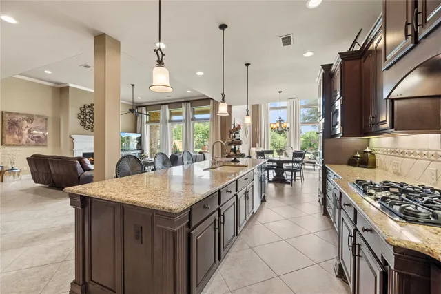a kitchen with kitchen island a dining table chairs stainless steel appliances and cabinets