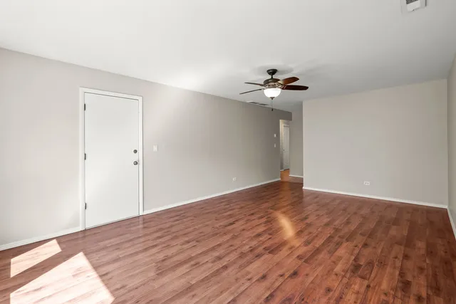 a view of a room with wooden floor and a ceiling fan