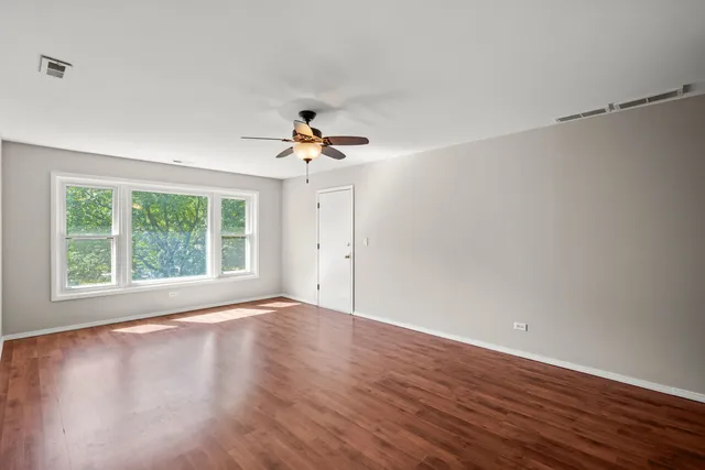a view of an empty room with a window and wooden floor