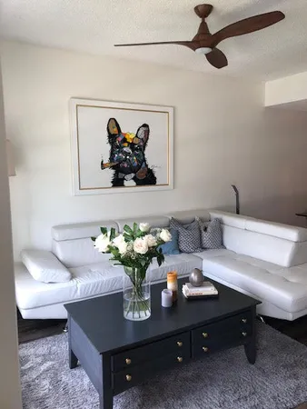 a living room with a couch a dining table wooden floor and a view of kitchen