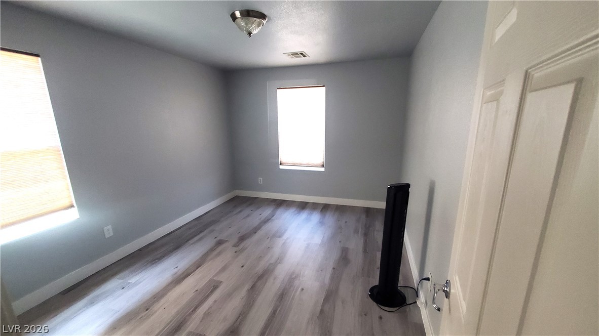 7903 Dell Ridge Avenue Las Vegas, NV 89179 - Photo 17 of 20 A well-lit bedroom with fresh gray walls and durable wood-look flooring awaits personalization.