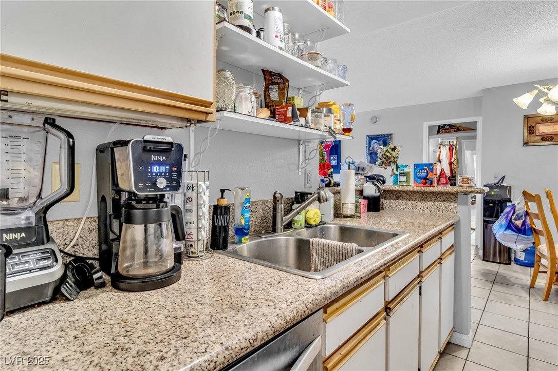 2200 South Fort Apache Road, Unit 1007 Las Vegas, NV 89117 - Photo 10 of 30 Kitchen featuring light tile patterned floors, open shelves, white cabinetry, a sink, and dishwasher