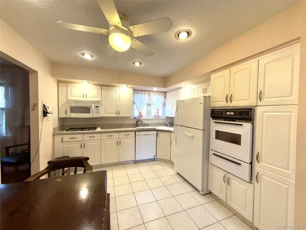 a kitchen with white cabinets and white appliances
