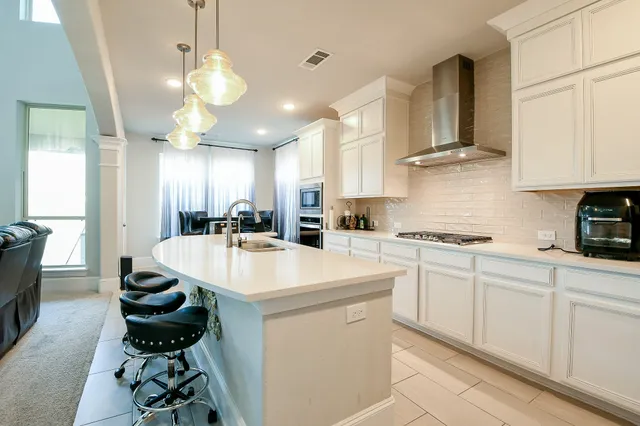 a kitchen with stainless steel appliances kitchen island granite countertop a sink a stove and a refrigerator