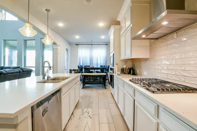 a kitchen with stainless steel appliances a sink a stove top oven a counter space and cabinets