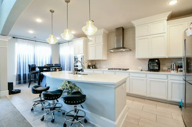 a kitchen with stainless steel appliances a stove a sink a refrigerator and chairs