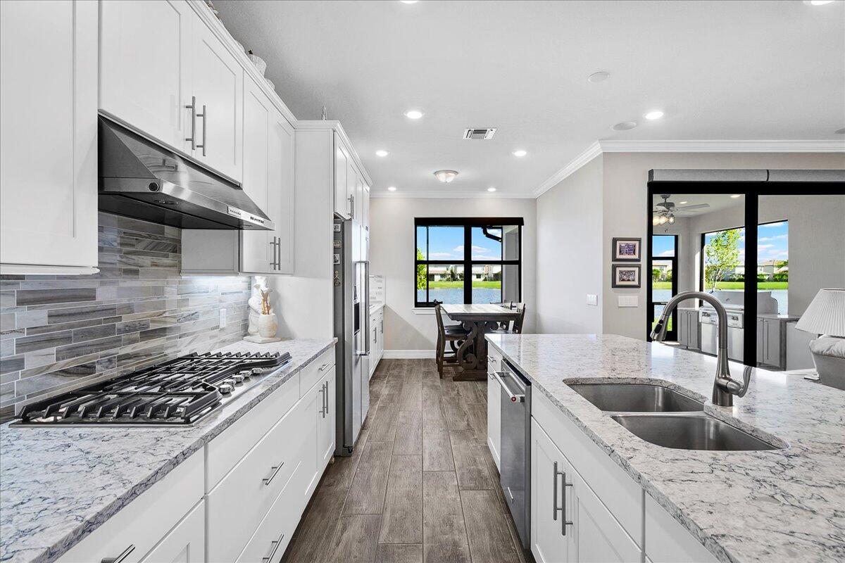 8311 Pedigree Circle Lake Worth, FL 33467 - Photo 6 of 37 a kitchen with stainless steel appliances granite countertop a sink a stove and a wooden floors