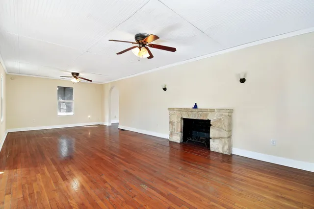 a view of an empty room with wooden floor and a fireplace