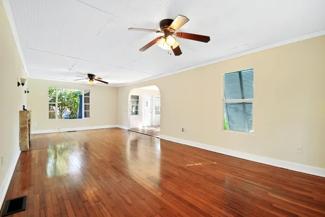 a view of an empty room with wooden floor and a window