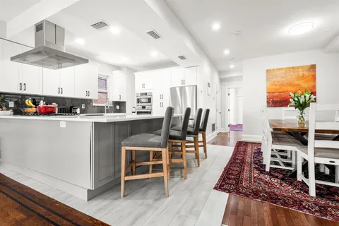 a kitchen with stainless steel appliances a stove a refrigerator a dining table and chairs with wooden floor