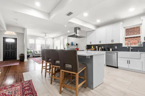 a kitchen with stainless steel appliances granite countertop a stove a sink dishwasher a dining table and chairs with wooden floor