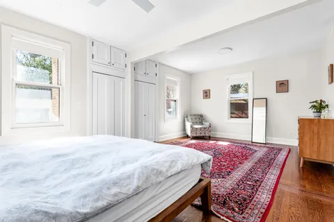 a bedroom with a large bed rug and wooden floor