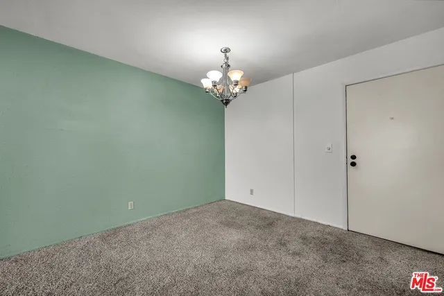 a view of an empty room with a chandelier fan