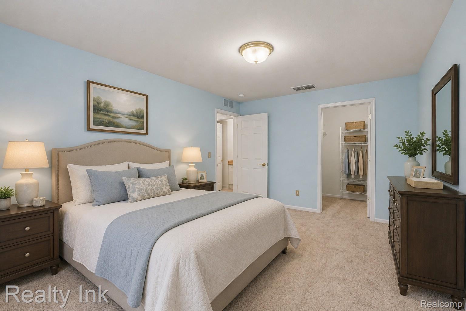 Bedroom featuring light carpet and a walk in closet