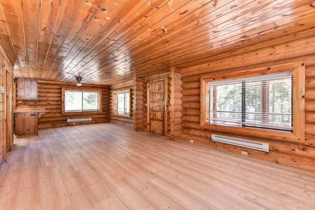 a view of a livingroom with wooden floor a ceiling fan and windows