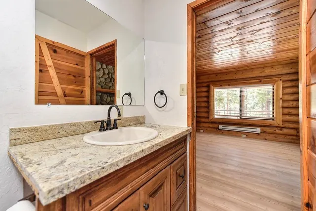 a kitchen with granite countertop white cabinets a window and wooden floor