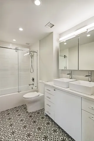 a bathroom with a toilet a sink a mirror a bathtub and shower