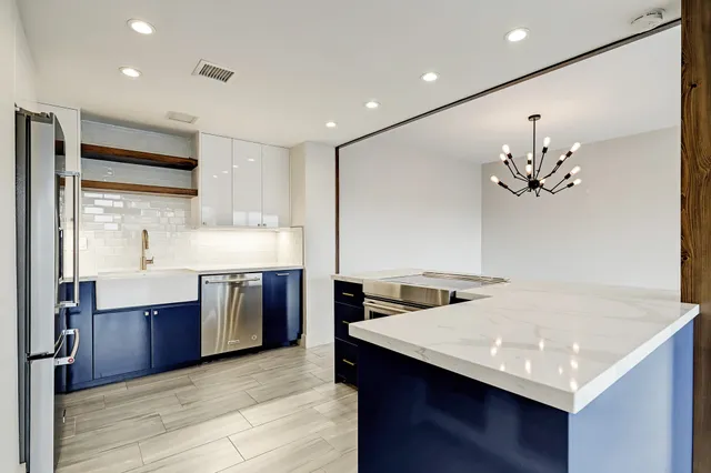 a kitchen with stainless steel appliances granite countertop a sink dishwasher and a stove with wooden floor