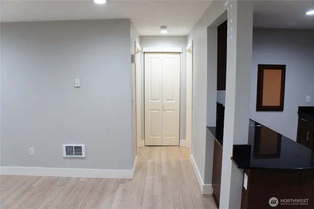 a view of a hallway with wooden floor and a bathroom