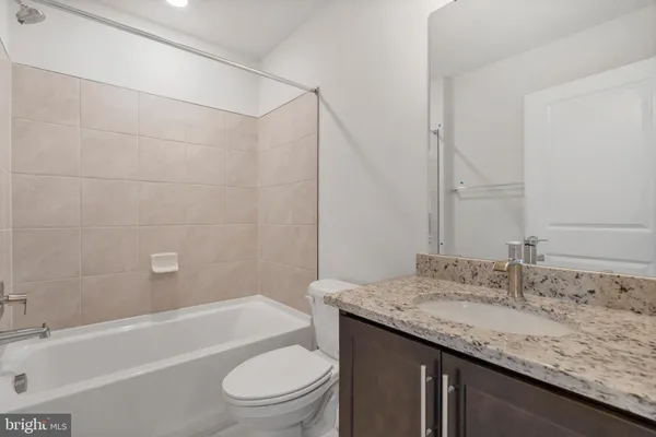 a bathroom with a granite countertop sink a toilet and bathtub