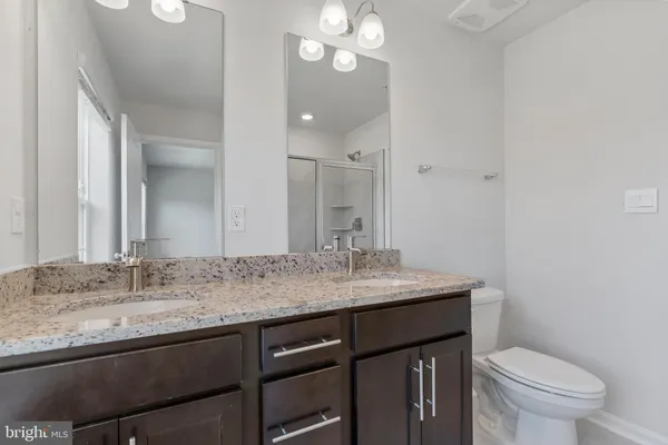 a bathroom with a granite countertop sink a toilet and a mirror