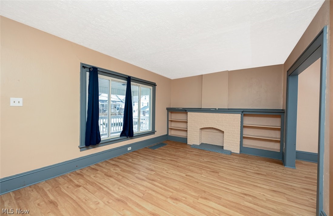 77 West Mildred Avenue Akron, OH 44310 - Photo 6 of 40 Unfurnished living room with light wood-style floors and a brick fireplace