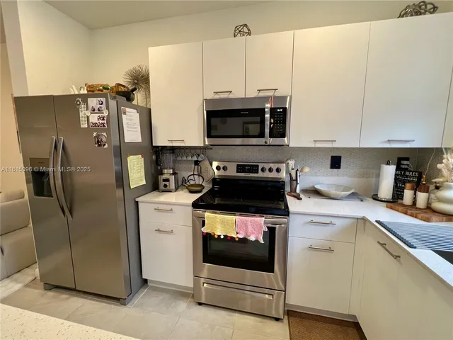 a kitchen with a sink a stove and white cabinets