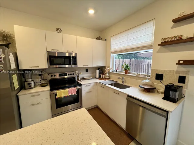 a living room with furniture kitchen view and a chandelier