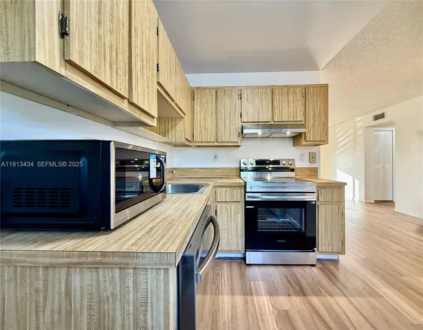 a kitchen with stainless steel appliances granite countertop a stove top oven a sink and a refrigerator