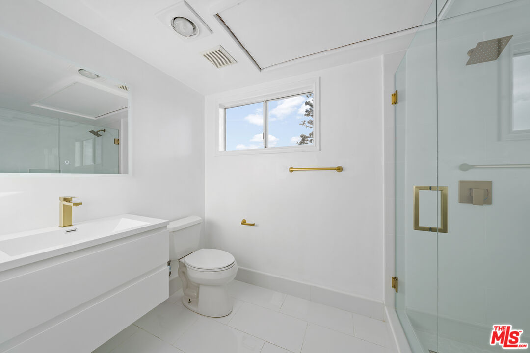 11606 Chenault Street, Unit 403 Los Angeles, CA 90049 - Photo 7 of 21 a bathroom with a granite countertop sink a toilet and shower