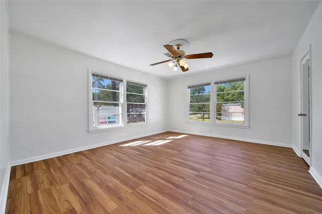 a view of an empty room with a window and wooden floor