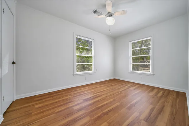 a view of an empty room with wooden floor and a window