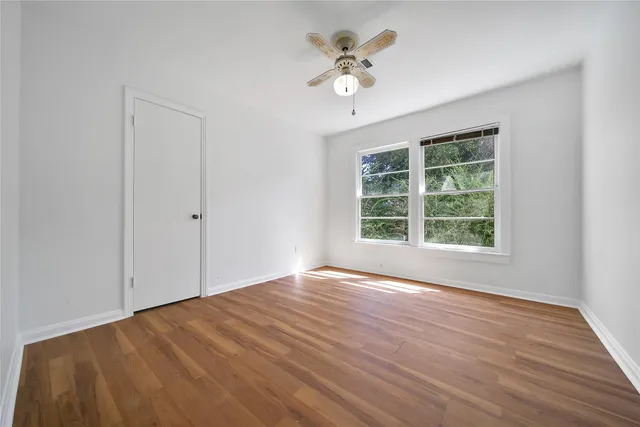 a view of an empty room with a window and wooden floor