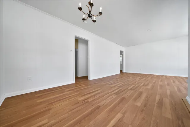 a view of empty room with wooden floor and ceiling fan