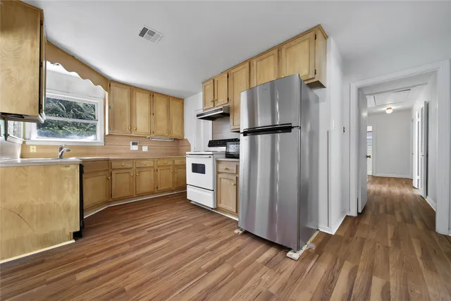 a kitchen with wooden floors and white stainless steel appliances