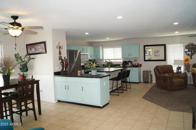 a kitchen with stainless steel appliances a sink a stove a refrigerator cabinets and a dining table