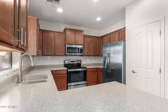 a kitchen with stainless steel appliances granite countertop a refrigerator stove microwave and sink