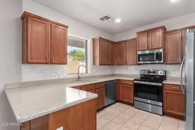 a kitchen with stainless steel appliances granite countertop wooden cabinets a stove top oven a sink and dishwasher