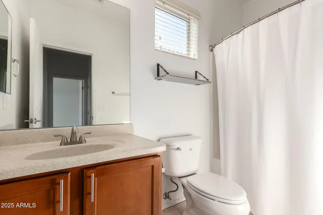 a bathroom with a granite countertop sink toilet and a mirror