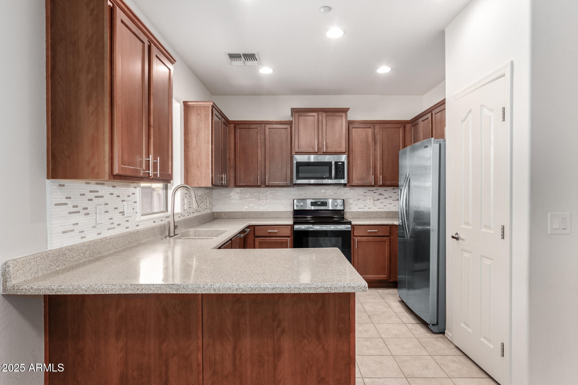 15820 North 74th Drive Peoria, AZ 85382 - Photo 10 of 33 a kitchen with a refrigerator a sink a stove a microwave and wooden cabinets