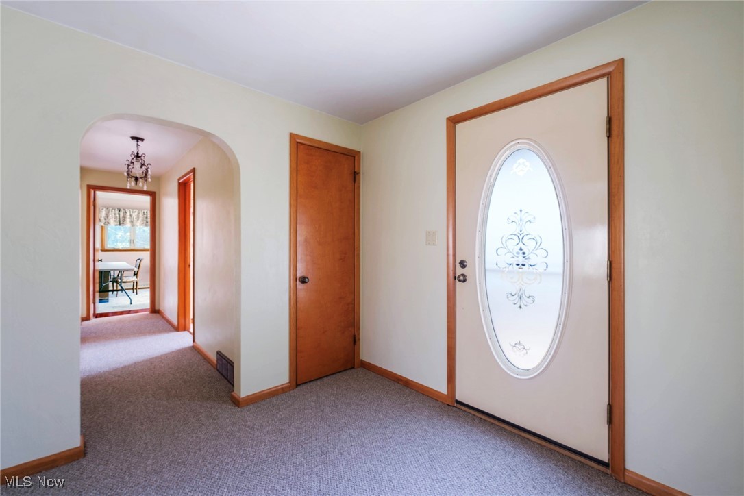 7059 Stewart Sharon Road Hubbard, OH 44425 - Photo 26 of 49 Foyer entrance featuring visible vents, light carpet, arched walkways, an inviting chandelier, and baseboards