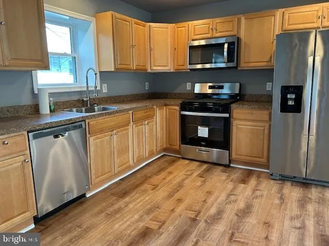 a kitchen with stainless steel appliances granite countertop a stove a sink and a refrigerator