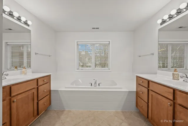 a spacious bathroom with a double vanity sink a mirror and a bathtub