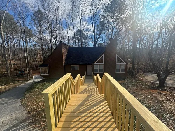 a view of house with wooden deck and trees
